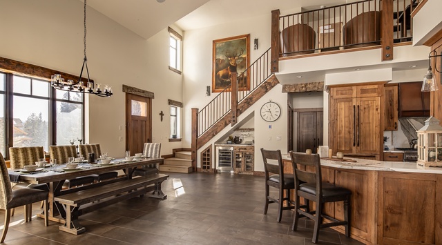 Gather around your rustic dining table where warm wood tones and soaring ceilings create the perfect mountain lodge atmosphere for memorable meals.