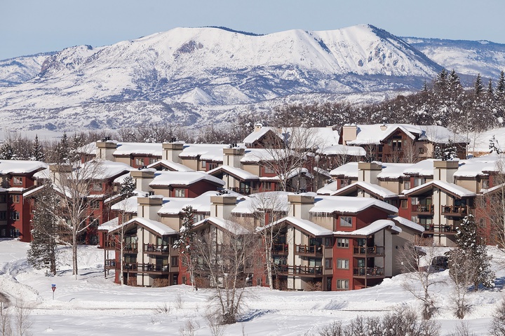 A mountain resort complex nestled among snow-covered peaks and forested slopes, offering convenient access to winter recreational activities in a scenic alpine setting.