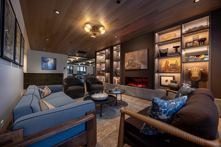 Sink into plush seating around the fireplace, where warm woods and curated shelves create your perfect retreat for evening conversation or quiet reading.