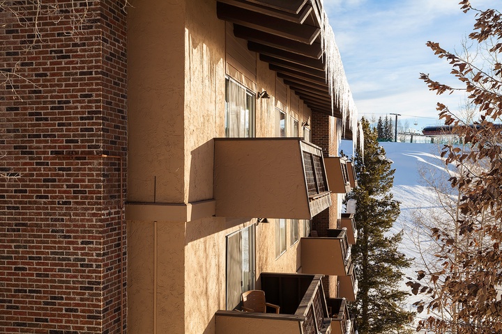 Mountain slope lodging with private balconies overlooking winter ski terrain and wooded areas. Each level opens to crisp alpine air and surrounding evergreen scenery.