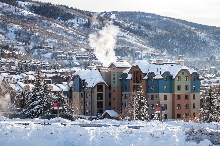 Winter alpine village nestled at the base of snow-covered mountain slopes, surrounded by evergreen forests and scenic peaks—an idyllic location for a mountain getaway.
