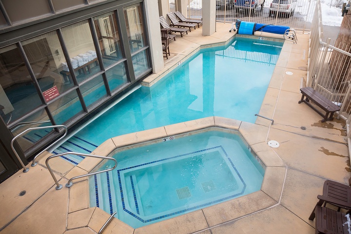 An indoor pool and hot tub area with loungers and glass doors opening to adjacent rooms, offering relaxation and year-round swimming.