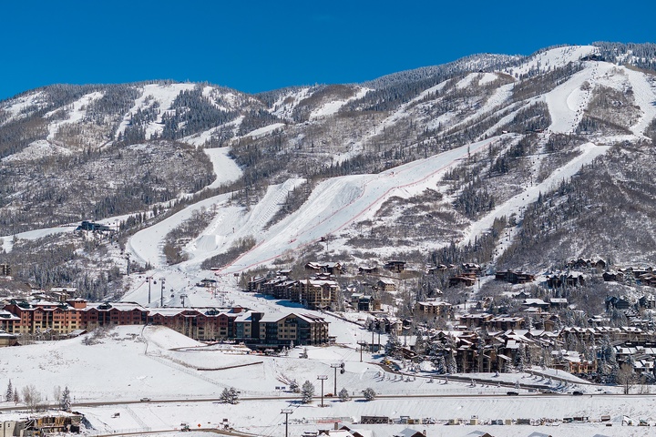 A winter resort nestled in pristine snow-covered mountains, featuring groomed ski runs and charming alpine lodges throughout the valley.