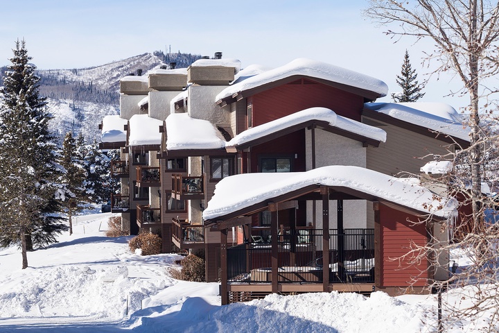 A picturesque winter retreat nestled in snowy mountain terrain, featuring inviting architecture and panoramic views of pristine slopes and forested peaks.