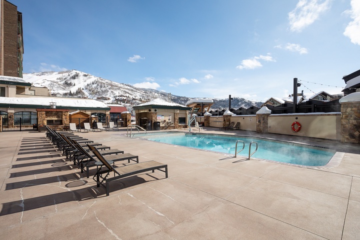 An outdoor heated pool with stunning mountain backdrop offers year-round relaxation. Lounge chairs line the deck, perfect for soaking up alpine sunshine after a day on the slopes.