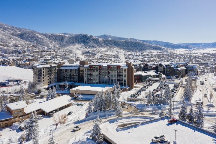 Aerial view of a winter resort nestled in snow-covered mountain terrain, offering access to skiing and outdoor recreation in a scenic alpine town.