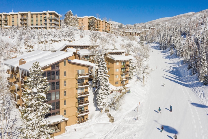Ski-in location nestled on the mountainside, surrounded by snow-covered evergreens and pristine winter slopes, with easy access to nearby lifts and trails.