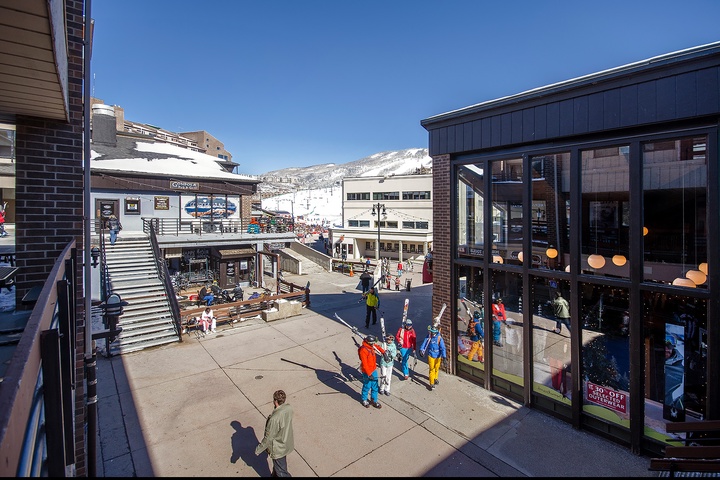 A vibrant ski village plaza surrounded by snow-dusted peaks, bustling shops, and mountain charm—your alpine adventure starts here.