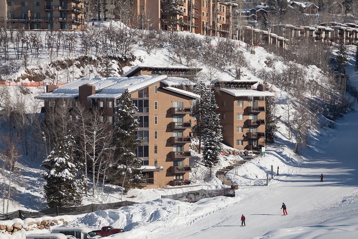 Ski-in location nestled at the base of groomed slopes, surrounded by snow-dusted pines and hillside lodges in a vibrant winter resort village.