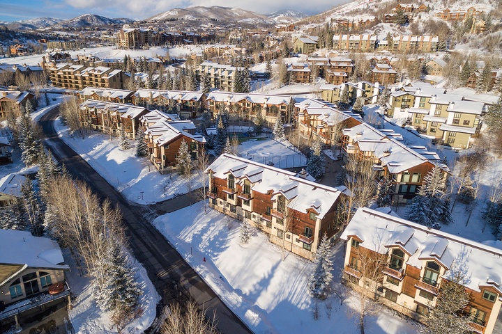 A picturesque mountain resort community blanketed in fresh snow, surrounded by snow-capped peaks and evergreen forests, offering a scenic alpine setting for winter getaways.