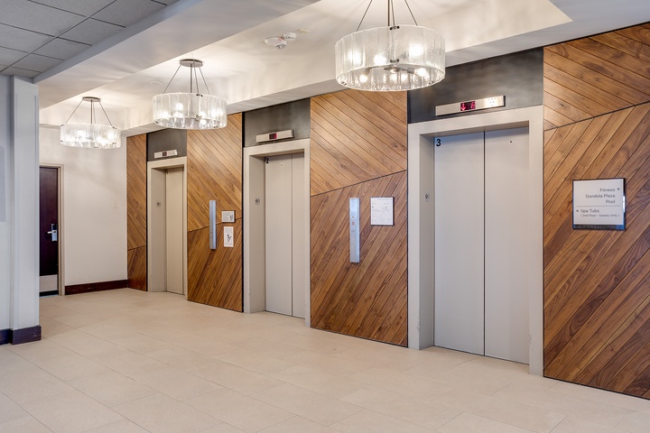 The elevator lobby welcomes you with contemporary design featuring diagonal wood paneling and elegant lighting for easy floor access.