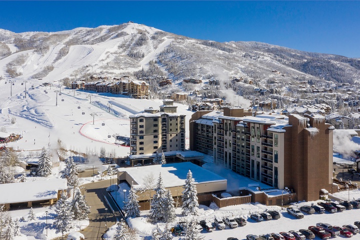 A premier ski resort village nestled at the base of snow-covered slopes, with ski lifts ascending the mountain, resort buildings blending into the winter landscape, and nearby lodging and amenities for a complete mountain getaway.