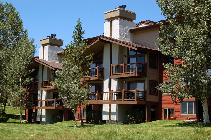 A multi-level mountain property with private balconies, stone fireplaces, and warm wood accents, set among aspens and evergreens on manicured grounds.