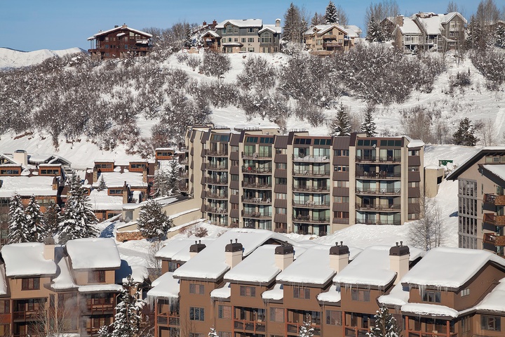 Snow-covered mountain resort community featuring multi-story lodges and chalets nestled among frosted evergreens, offering convenient access to winter slopes and alpine recreation.