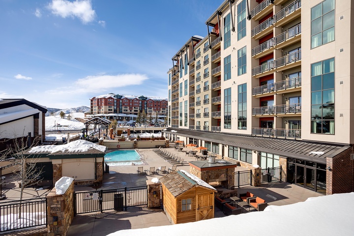 A spacious ski resort complex featuring heated outdoor pool, hot tub, fire pit lounge, and mountain views—perfect for après-ski relaxation.