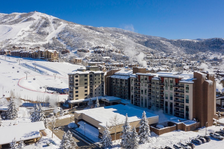 Aerial view of the property nestled at the base of snow-covered ski slopes in a scenic mountain resort town, offering convenient slope-side access.