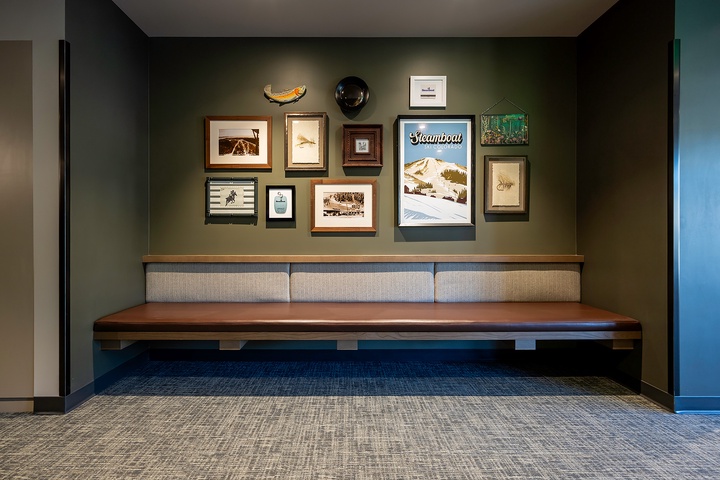 Styled seating area features curated wall art celebrating local mountain culture and outdoor adventure, with a warm wooden bench providing a cozy spot to relax.