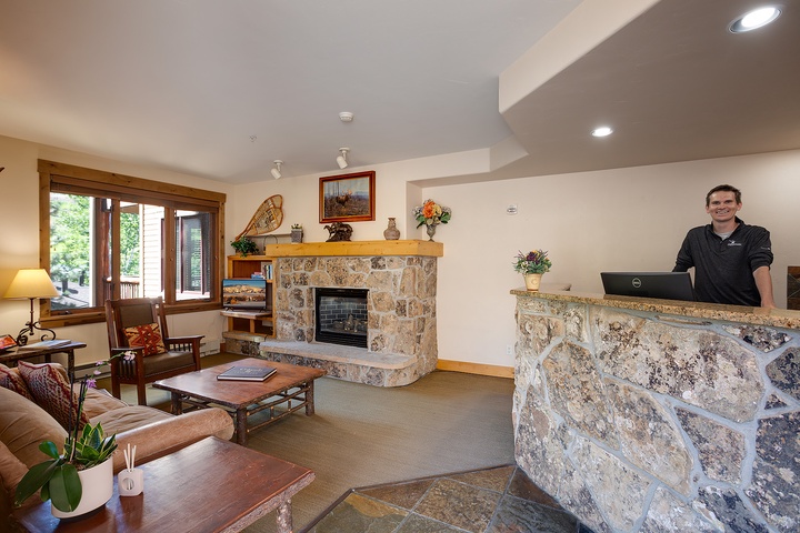 Welcome desk with friendly staff ready to greet you in a cozy lobby with stone fireplace and comfortable seating for your arrival.