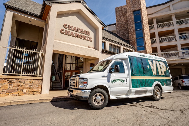 The Chateau Chamonix resort entrance stands alongside a VIP shuttle van ready to transport guests, offering convenient access to nearby attractions and lodging in the area.