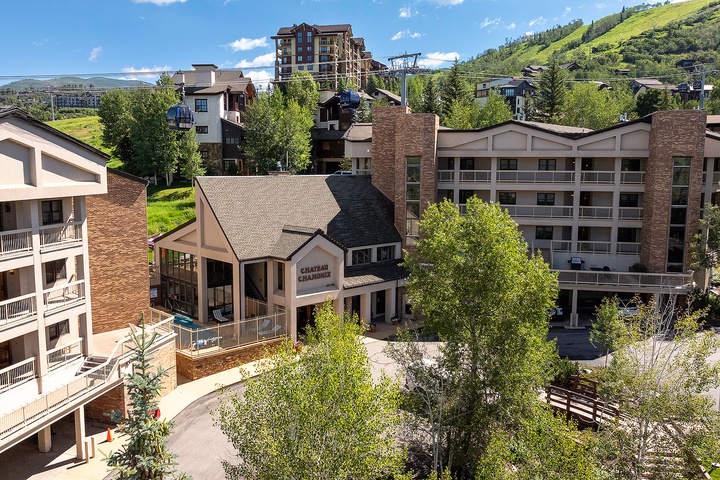 The Chateau Chamonix nestles in a picturesque mountain village, surrounded by lush hillsides and alpine architecture, offering a serene arrival experience.