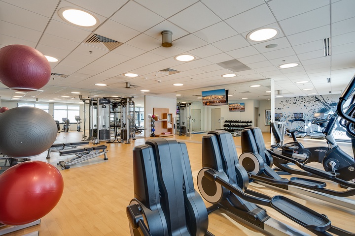 Stay active in this modern fitness center with cardio machines, free weights, and exercise balls—all flooded with natural light to energize your workout routine.