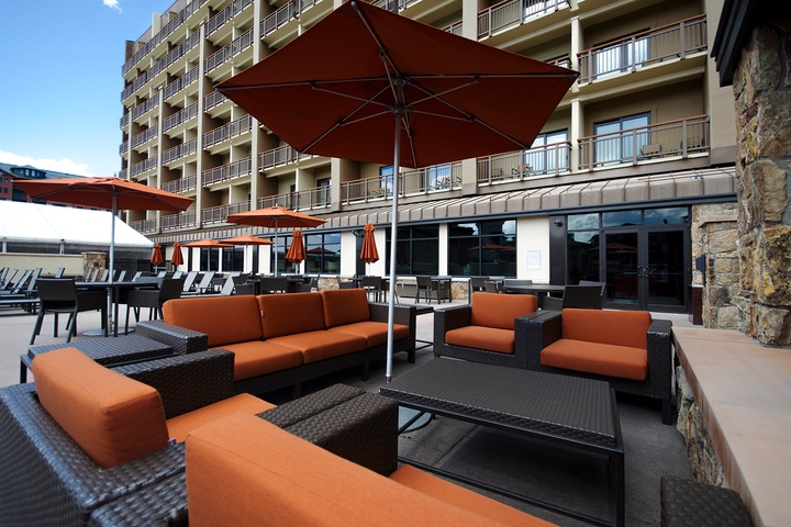 This inviting outdoor lounge area with property structure in the background offers a perfect setting for relaxation. Comfortable seating and shaded areas provide a welcoming space to unwind during your stay.