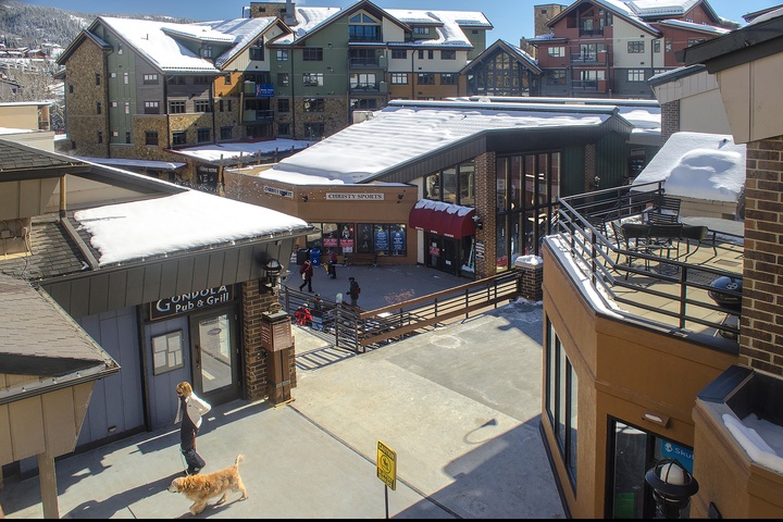 Elevated view of the surrounding village area during winter, featuring nearby shops, restaurants, and snow-covered alpine buildings that frame the resort neighborhood.