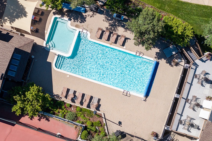 Aerial view of the property features a sparkling pool with hot tub, surrounded by lounge chairs, lush landscaping, and outdoor dining areas—a private oasis perfect for relaxation.