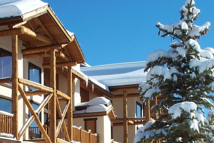 Snow-covered alpine lodge with frosted evergreen and bright blue skies sets the scene for a perfect winter mountain escape.