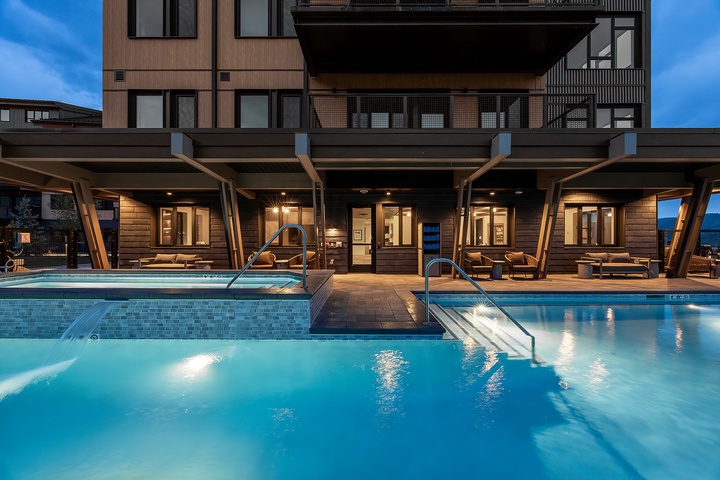 Modern mountain property featuring outdoor pools and covered lounge areas, captured during the tranquil twilight hour.