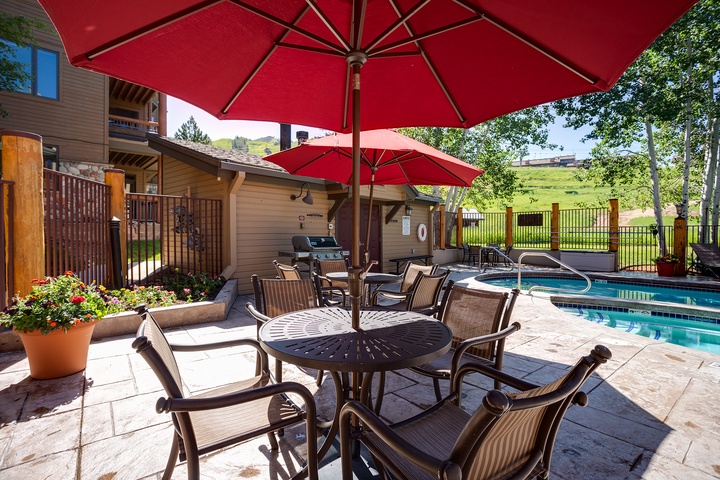 Relax poolside under vibrant red umbrellas, surrounded by rolling green hills and mountain views. Your own outdoor oasis awaits, complete with a hot tub, grill, and inviting patio seating.