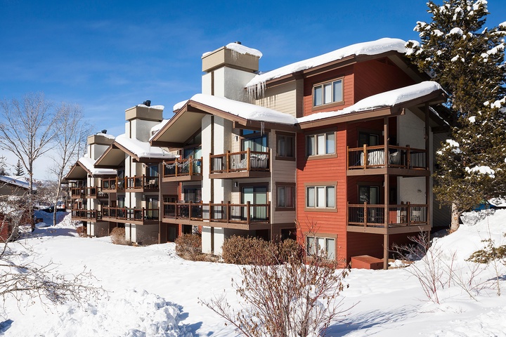 This multi-unit mountain property features spacious balconies and modern alpine architecture set against a pristine winter landscape, perfect for ski season getaways.