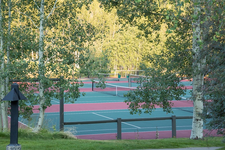 Tennis courts framed by golden aspens offer a scenic setting for active recreation near the property.