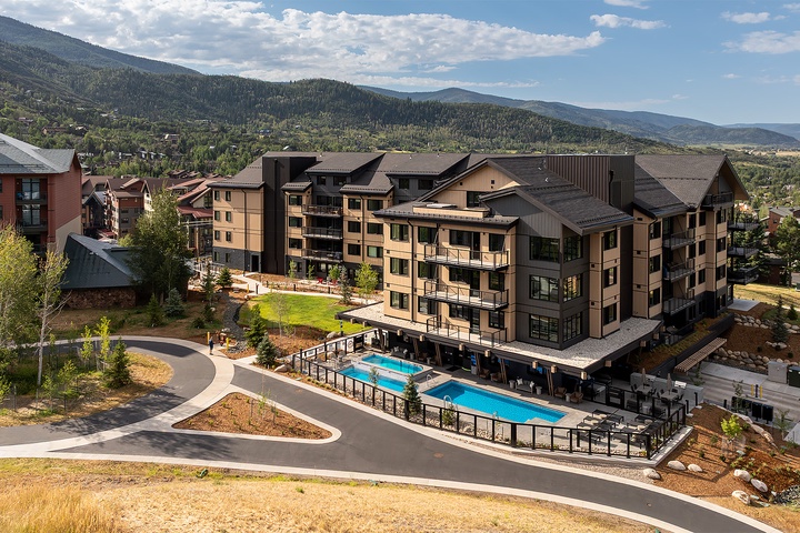 A contemporary mountain property featuring alpine architecture and scenic placement amid forested slopes. The community features modern multi-story residences, outdoor pool facilities, and convenient access to surrounding recreational terrain.