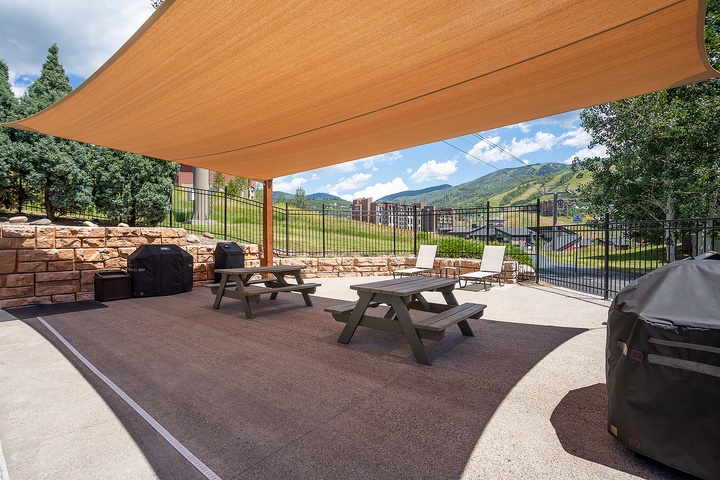 Shaded outdoor area with picnic tables and multiple grills framed by stunning mountain views—perfect for casual cookouts and gathering with friends or family in the fresh air.