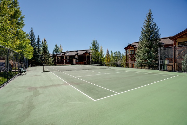 Private tennis court with mountain and forest backdrop, offering outdoor recreation during your mountain getaway.