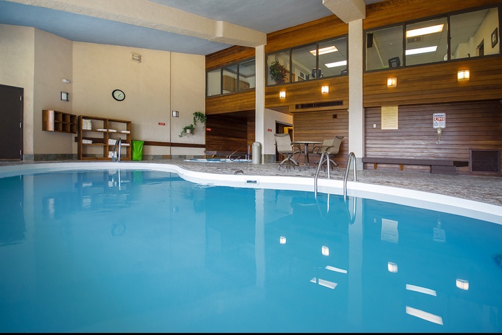An inviting indoor pool surrounded by warm wood accents, with poolside seating and upper-level viewing areas for a relaxing swim experience.