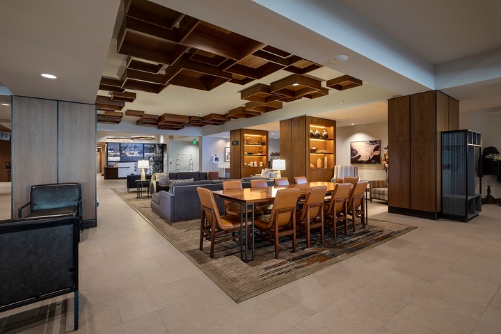 Modern lobby with a striking geometric wood ceiling, plush seating, and a large communal table perfect for gathering with fellow travelers.