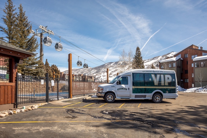 A ski resort shuttle parked at the base, with gondola lifts rising toward snowy mountain slopes—convenient transportation to the slopes.