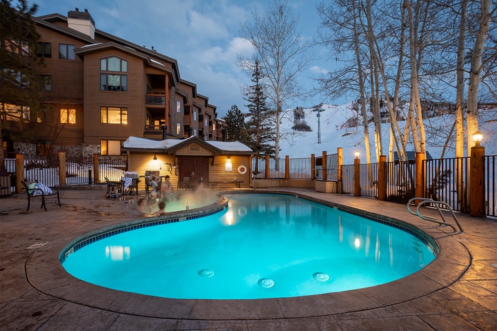 Outdoor pool and hot tub area at twilight, offering mountain slope views and perfect après-ski relaxation after a day on the slopes nearby.