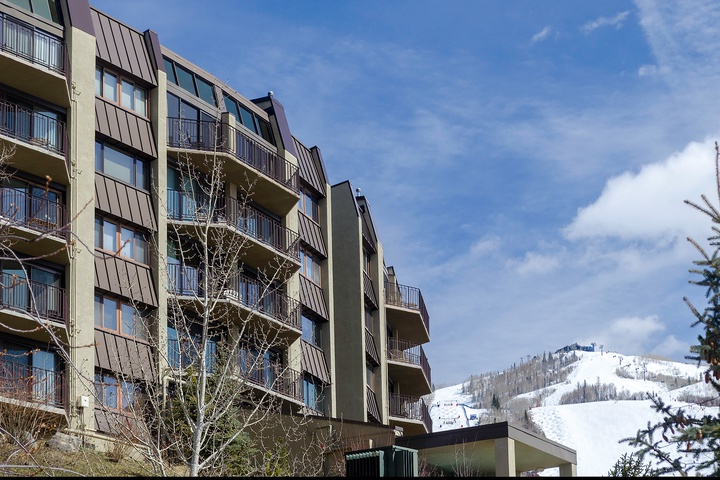 Multi-story vacation rental building set against snow-covered mountain slopes, offering ski-in/ski-out access and stunning alpine scenery in a prime winter resort location.