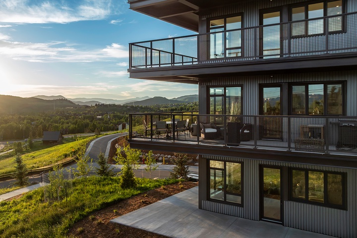 Modern multi-level property nestled in a serene mountain setting with sweeping views and spacious balconies bathed in golden evening light.