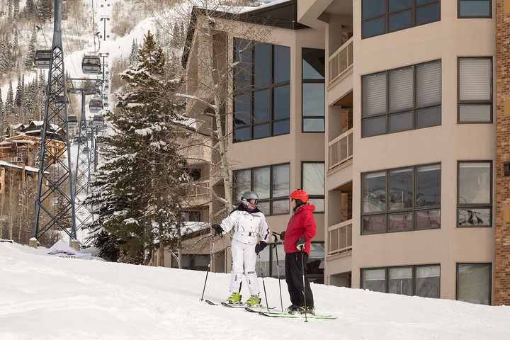Ski-in, ski-out property situated directly on the slopes with a chairlift nearby. Modern multi-level building with balconies overlooking the snowy mountain terrain.