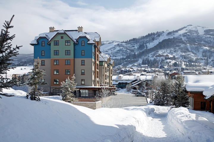 Colorful alpine property nestled in a snow-covered village, with ski slopes rising in the background—a perfect mountain retreat setting.