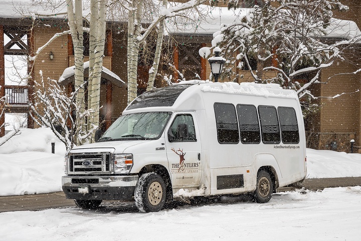 The Antlers shuttle stands ready in fresh snowfall, framed by frosted aspen trees and winter's quiet beauty near the property.