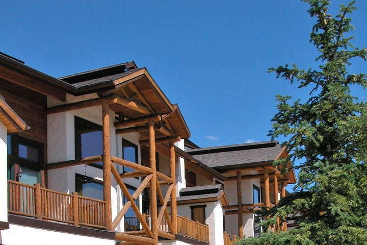 A charming mountain-style property featuring timber balconies and exposed wood beams set against a clear blue sky.