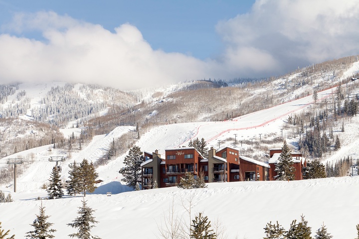 Modern slope-side residences nestled at the base of pristine ski runs, surrounded by snow-covered evergreens and alpine terrain, offering immediate access to winter recreation.