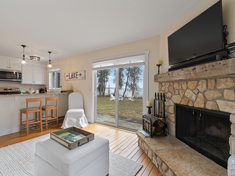 Updated and comfortable main living space offers a wood burning fireplace, SMART TV, and views of the private lakeshore