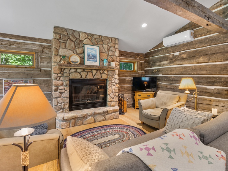 The cozy living room offers plenty of comfortable seating and a wood burning fireplace
