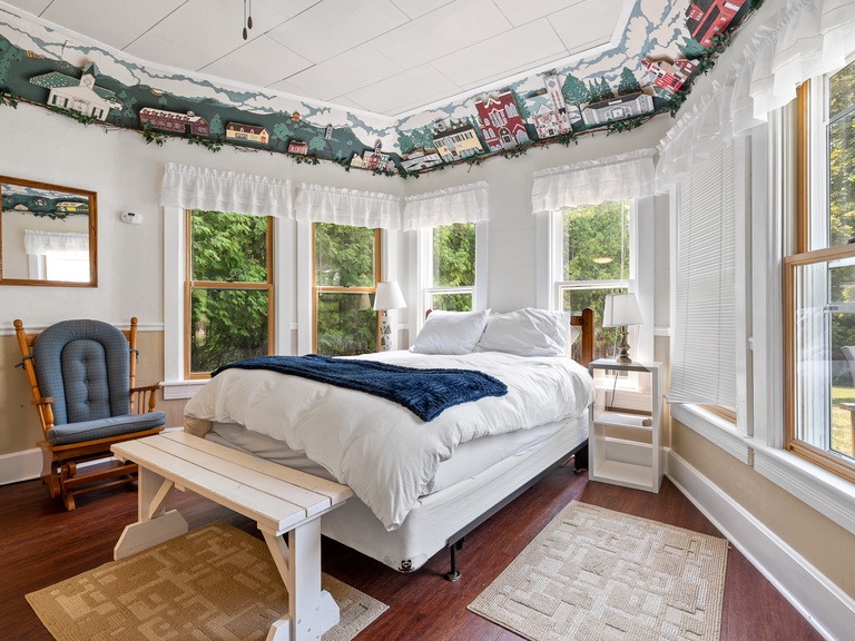 Queen size bed is surrounded by windows